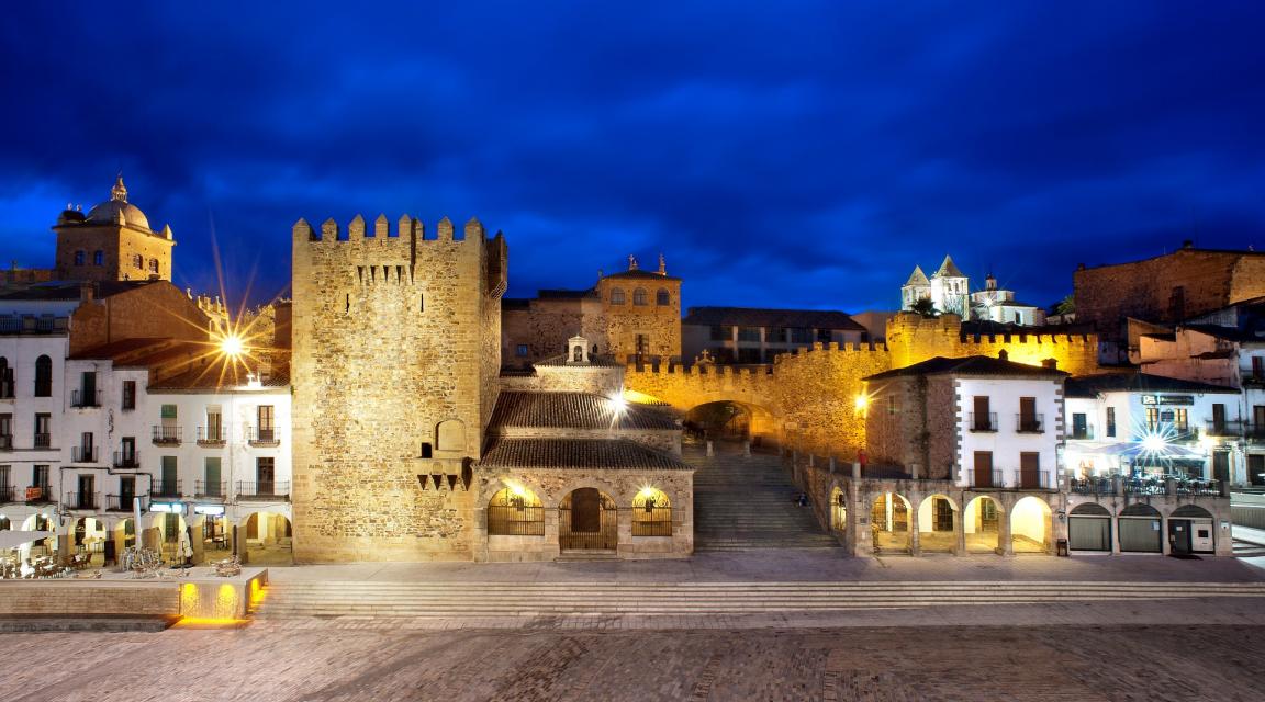 Plaza Mayor de Cáceres iluminada de noche, con la Torre de Bujaco y el Arco de la Estrella